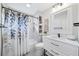 Well-lit bathroom featuring shower with blue leaf shower curtain, shelving, and modern vanity at 9250 Nesbit Lakes Dr, Alpharetta, GA 30022