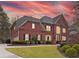 Stunning two-story brick home featuring manicured lawn and a warm, inviting facade at sunset at 9250 Nesbit Lakes Dr, Alpharetta, GA 30022