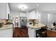 Modern kitchen with white cabinets, stainless steel appliances, granite countertops, breakfast bar and dark wood floors at 3335 Maple Terrace Dr, Suwanee, GA 30024