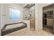 Bathroom featuring a walk-in shower with tile surround and soaking tub under a window at 1226 Goodwin Ne Rd, Atlanta, GA 30324