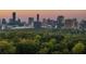 View of the city skyline rising behind lush treetops at dusk with various office and residential buildings at 1226 Goodwin Ne Rd, Atlanta, GA 30324