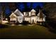 Stately home featuring a stone chimney, manicured lawn, mature landscaping, and charming exterior lighting at 1226 Goodwin Ne Rd, Atlanta, GA 30324