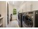 Laundry room with stainless steel washer and dryer, white storage cabinets, and a window at 1226 Goodwin Ne Rd, Atlanta, GA 30324