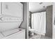 Stacked washer and dryer next to a shower with gray tiling and white curtain at 2077 Alcovy Trace Way, Lawrenceville, GA 30045