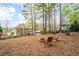Large backyard with play structure, fire pit and mature trees, offering space for outdoor fun and relaxation at 111 Glen Trl, Woodstock, GA 30188