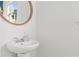 Clean and modern bathroom featuring a pedestal sink and a round mirror at 1736 Brookside Lay Cir, Norcross, GA 30093