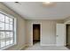 A simple, carpeted bedroom featuring a large window, closet, and a white door at 591 Paper Ridge Ct, Lawrenceville, GA 30046