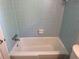 Classic white bathtub with blue tile surround and chrome fixtures in the bathroom at 3013 Barcelona Way, Conyers, GA 30012