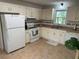 Close-up of the kitchen with white appliances, cabinets, and a window at 3013 Barcelona Way, Conyers, GA 30012
