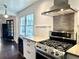 Close-up of kitchen features stainless steel oven range, vent, textured backsplash, and wine fridge with a view to the outdoors at 1828 Kellogg Creek Rd, Acworth, GA 30102