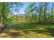 Spacious backyard with lush greenery, a tranquil lake, and a charming greenhouse nestled among the trees at 2210 Hamstead Ct, Suwanee, GA 30024
