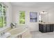 Bright bathroom features soaking tub, vanity with dark cabinets, and picture window with natural light at 2210 Hamstead Ct, Suwanee, GA 30024