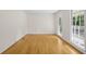 Bright, unfurnished room with gleaming hardwood floors, white walls, and large windows offering natural light at 2210 Hamstead Ct, Suwanee, GA 30024