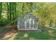 Quaint greenhouse on a well-maintained lawn, framed by trees, offers a serene gardening space at 2210 Hamstead Ct, Suwanee, GA 30024