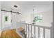 Upstairs hallway provides access to other rooms, with hardwood floors and a decorative barn door at 2210 Hamstead Ct, Suwanee, GA 30024