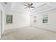 Bright main bedroom features tray ceiling, neutral carpet, ceiling fan, and windows offering natural light at 2210 Hamstead Ct, Suwanee, GA 30024