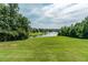Scenic view of a tranquil lake surrounded by lush greenery from a grassy lawn at 3853 Coralberry Ct, Dacula, GA 30019