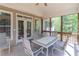 This screened porch has wood trim, a tile floor, and a table with seating for four people at 3853 Coralberry Ct, Dacula, GA 30019