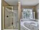 Bright bathroom featuring a jetted tub with a window view and a separate shower with gold trim at 8100 Greens Mill Way, Loganville, GA 30052