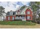Charming two-story brick home with a covered front porch and well-manicured landscaping at 8100 Greens Mill Way, Loganville, GA 30052