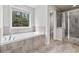 Bathroom featuring soaking tub, window with backyard view, and tiled walk-in shower at 104 Marlow Dr, Woodstock, GA 30188