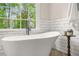 Freestanding tub with modern fixtures next to a window with natural light and suburban backyard views at 750 Southland Pass, Stone Mountain, GA 30087