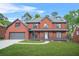 Charming two-story red brick home with inviting front porch, well-manicured lawn, and attached garage at 750 Southland Pass, Stone Mountain, GA 30087