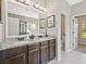 Well-lit bathroom featuring double vanity, granite countertops, framed mirror, and modern fixtures at 125 Leverett Ct, Fayetteville, GA 30215