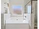 Bright bathroom featuring a soaking tub, tiled walls, and a frosted window for privacy at 125 Leverett Ct, Fayetteville, GA 30215