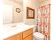 Cozy bathroom with a vanity, toilet, shower with a colorful curtain, clock, and an eye-catching picture at 2904 Ridgeview Sw Dr, Atlanta, GA 30331