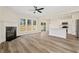 Open-concept living area with hardwood floors, a fireplace, large windows, and a view into the modern kitchen at 5620 Weddington Drive Dr, Cumming, GA 30040