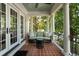 Relaxing covered porch features brick pavers, comfortable wicker seating, and white pillars at 123 Peachtree Cir, Atlanta, GA 30309