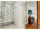 Close-up view of a glass-enclosed shower with mosaic tile and bench, adjacent to a hardwood floored area at 123 Peachtree Cir, Atlanta, GA 30309