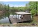 Wooden dock with a covered seating area extending onto the calm lake at 7650 Rico Rd, Chattahoochee Hills, GA 30268