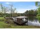 View of a covered dock extending into a calm lake, surrounded by trees at 7650 Rico Rd, Chattahoochee Hills, GA 30268