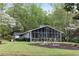 The screened-in porch offers a serene view of the landscaped yard and lake at 7650 Rico Rd, Chattahoochee Hills, GA 30268