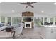 Open-concept living room featuring large windows, stone fireplace, and screened in patio access at 7650 Rico Rd, Chattahoochee Hills, GA 30268
