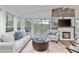 Sun-filled living room with a stone fireplace, plush seating, and large windows overlooking the lake at 7650 Rico Rd, Chattahoochee Hills, GA 30268
