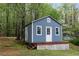 A quaint blue outbuilding with a small porch in a wooded setting at 7650 Rico Rd, Chattahoochee Hills, GA 30268