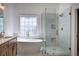 A bright bathroom features a soaking tub, glass shower, decorative window, and double sink vanity at 1043 Middlebrooke Dr, Canton, GA 30115