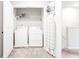Bright laundry room with washer, dryer, shelving, and ironing board for convenient chores at 7154 Sw Chara Sw Ln, Atlanta, GA 30331