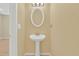 Cozy powder room featuring a pedestal sink, oval mirror, and modern lighting creating a clean and functional space at 7112 Brookview Way, Riverdale, GA 30274