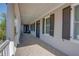 Long porch with wood-look tile, white columns, and black doors and shutters at 3890 The Battery, Duluth, GA 30096