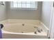 Large soaking tub with chrome fixtures and a window at 106 Creek Crossing Ln, Temple, GA 30179