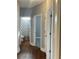Hallway view with hardwood floors and three doors with white trim, one open to a bathroom with a shower at 106 Creek Crossing Ln, Temple, GA 30179
