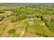 Aerial shot showcases a sprawling farm with multiple outbuildings and lush green pastures surrounded by dense woods at 1288 Reavesville Rd, Bowdon, GA 30108