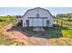 Large, white barn with sliding doors and a sheltered area on a vast lot at 1288 Reavesville Rd, Bowdon, GA 30108
