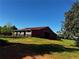 Charming red barn with a metal roof, horse stalls, and surrounding pasture for livestock grazing at 1288 Reavesville Rd, Bowdon, GA 30108