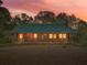Charming cabin illuminated at twilight, surrounded by lush trees; a serene retreat at 1288 Reavesville Rd, Bowdon, GA 30108