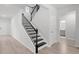 Elegant staircase with black iron railings and oak stairs adjacent to entry door and downstairs bathroom at 1815 Wellston Dr, Lawrenceville, GA 30043